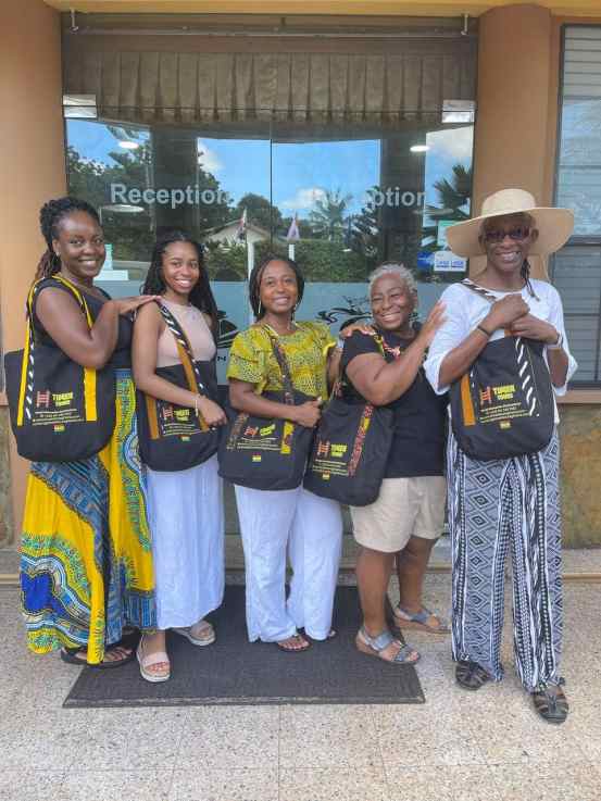 Tourists posing with Timeh Tours bags at hotel reception in Ghana