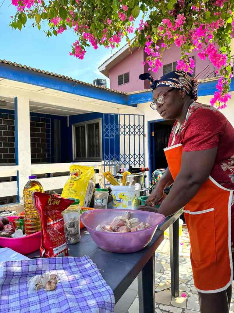 Local cooking instructor Auntie K teaching visitors how to prepare traditional Ghanaian food during a cooking class with Timeh Tours