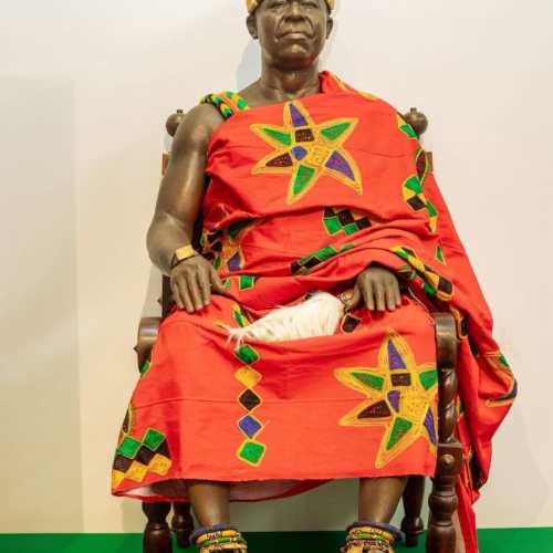 Ghanaian king statue dressed in traditional attire, seated on a throne, showcasing cultural heritage.